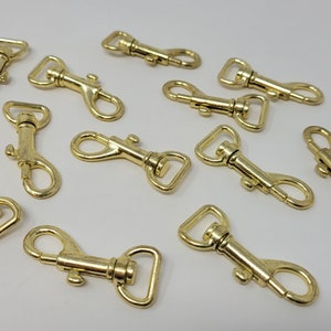 May include: A group of 10 gold-toned metal swivel snap hooks. The hooks are about 1 inch long and have a spring-loaded gate.