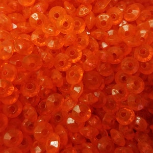 May include: A collection of small, round, translucent orange beads with a faceted surface and a central hole. Each bead features a circular shape with multiple angled cuts that reflect light, creating a bright, uniform orange appearance throughout.
