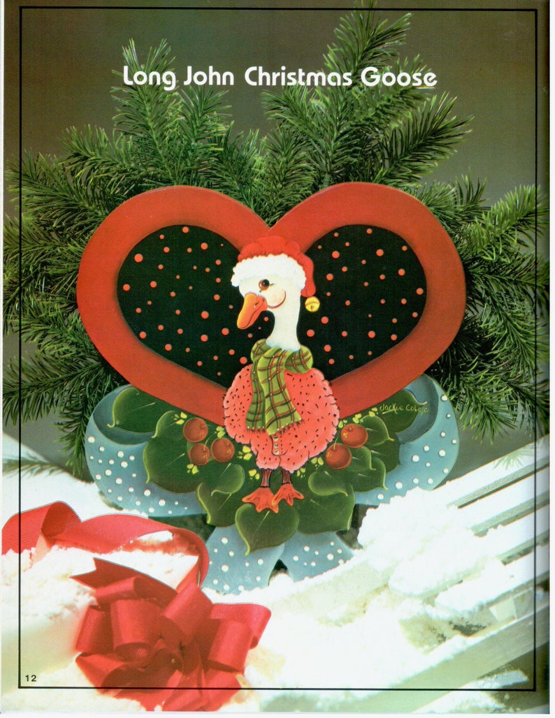 Puede incluir: Una decoraci&oacute;n navide&ntilde;a de madera en forma de coraz&oacute;n pintada a mano con un ganso que lleva un gorro de Pap&aacute; Noel y una bufanda a cuadros. El ganso est&aacute; rodeado de bayas rojas y hojas verdes. El coraz&oacute;n est&aacute; decorado con lunares negros y blancos y un borde rojo.