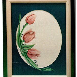 May include: A framed painting featuring three pink tulips with green leaves and small blue flowers. The tulips are arranged on a cream-colored oval against a dark teal background, enclosed in a light wood frame.