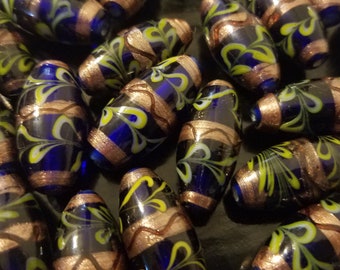 May include: A collection of blue and gold glass beads with a swirling pattern. The beads are oval shaped and have a glossy finish.