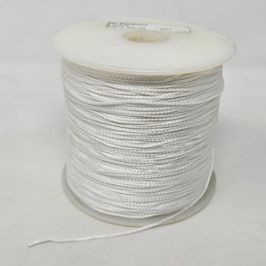 May include: A spool of white thread wound around a white plastic bobbin. The thread is smooth and appears to be made of a synthetic material.