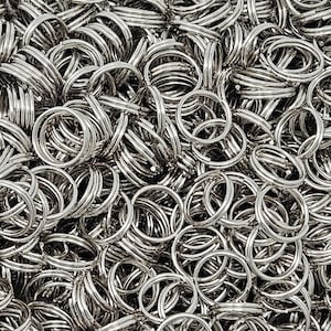 May include: A close-up shot showcases a large quantity of shiny, silver-colored key rings. The key rings are tightly packed together, creating a dense, textured surface. Each ring is a simple, circular design, reflecting light and adding to the overall metallic sheen.