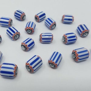 Puede incluir: Una colección de 17 cuentas de vidrio rayadas en azul, blanco y naranja con un diseño floral. Las cuentas son cilíndricas y tienen un acabado brillante.