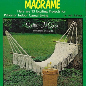 May include: A white macrame hammock swing hanging from a tree branch with a wicker basket and a glass of lemonade on a table in front of it. The book cover reads "The Sunny Side of Macrame: Here are 15 Exciting Projects for Patios or Indoor Casual Living" and "Swing-N-Sway: Instructions on page 22" by Judy Palmer.