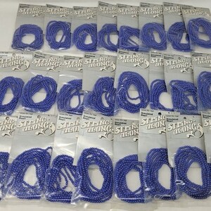 May include: Twenty-four packages of simulated pearl string-alongs in a blue color. Each package has the text "Simulated Pearl String-Along" printed on it.