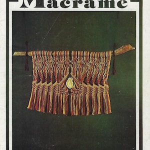 May include: A book titled "Turk's Head Book of Creations in Macrame" with a colourful macrame wall hanging featuring a shell in the centre.