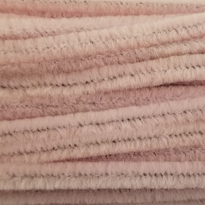 May include: A close-up of a bundle of pink pipe cleaners. The pipe cleaners are soft and fuzzy, and they are arranged in a neat pile.