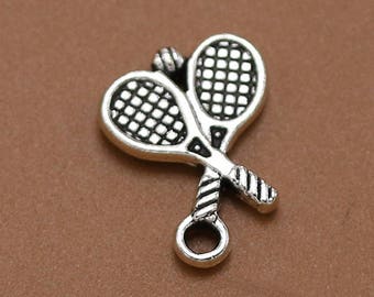 Może przedstawiać: Srebrny charm przedstawiający dwie skrzyżowane rakiety tenisowe z detalicznym wzorem siatki. Charm ma pętelkę do przymocowania do bransoletki lub naszyjnika.