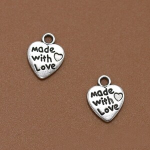 May include: Two silver heart-shaped charms with the words "Made with Love" and a small heart design.