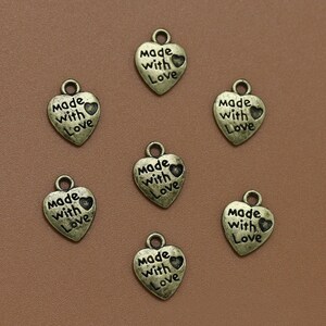 May include: Seven antique gold-toned heart-shaped charms with the words "Made with Love" engraved on each charm.