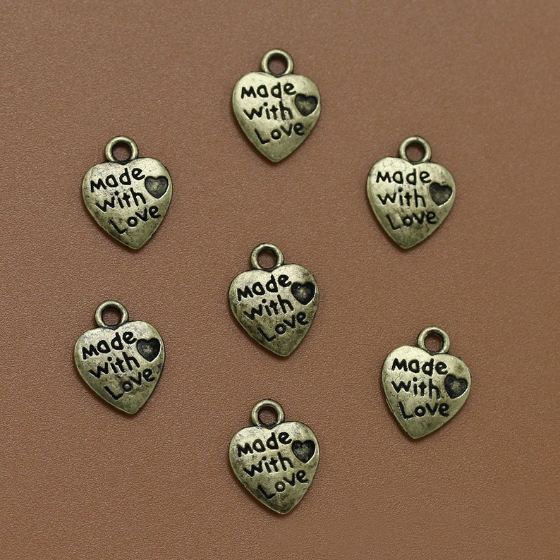 May include: Seven antique gold-toned heart-shaped charms with the words "Made with Love" engraved on each charm.
