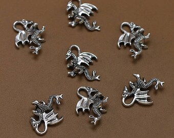 May include: Seven silver dragon charms with intricate details. The charms are in various poses, with wings spread and tails curled. They are perfect for adding a touch of fantasy to jewelry or crafts.