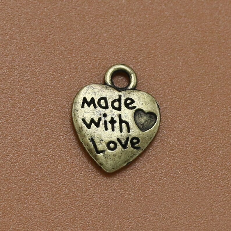 May include: A gold-toned heart-shaped charm with the words "Made with Love" and a small heart design.