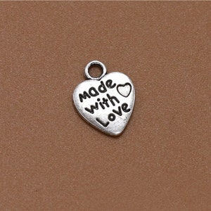 May include: Silver heart-shaped charm with the words "Made with Love" and a small heart.