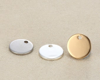 May include: Three metal disc charms in silver and gold. Each charm is round with a small hole at the top for stringing. The charms are blank and ready for customization. The charms are approximately 0.75 inches in diameter.