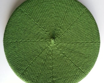 May include: A green knitted beret with a circular shape and a textured surface.