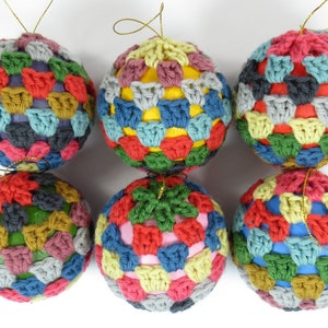 May include: Six colorful crocheted Christmas ornaments with a variety of colors including red, green, blue, yellow, and gray.