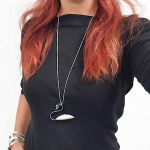 May include: A silver necklace with a swan pendant. The swan is made of metal and has a black head and a white body.