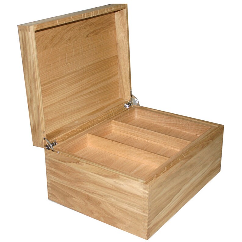 May include: A rectangular light brown wooden box with a hinged lid that is open. The interior of the box is divided into three separate compartments by two wooden dividers. The box features visible wood grain and silver metal hinges.