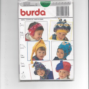 May include: A Burda sewing pattern envelope labeled 3956 for hats and caps. The front displays six different headwear designs, including a red patterned ear warmer, a blue patterned cap, a yellow pointed hat, and a red and blue beret style.