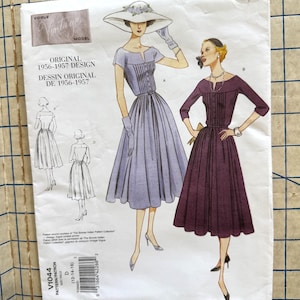 May include: A Vogue Vintage Model sewing pattern envelope for a 1956-1957 design, labeled V1044. The illustration features two variations of a dress with a pleated bodice and full skirt, one in light blue with a wide-brimmed hat and one in dark purple.