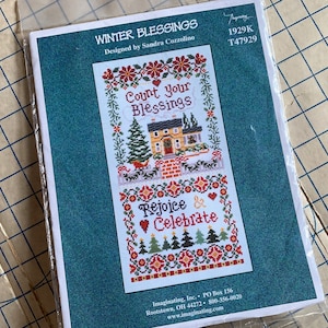 May include: A cross-stitch pattern featuring a winter scene with a house, trees, and the text "Count your Blessings" and "Rejoice & Celebrate".