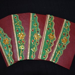 Könnte beinhalten: Fünf rote Umschläge mit grünem und goldenem Dekor. Der Besatz zeigt ein florales Design mit kleinen, bunten Schmucksteinen.