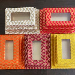May include: Set of six decorative boxes with intricate paisley patterns in shades of white, red, orange, and yellow. Each box has a rectangular window opening.