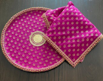May include: A round, pink tray with gold polka dots and a gold beaded border. A smaller, square pink cloth with gold polka dots and a gold beaded border is on top of the tray.