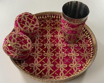 May include: A decorative set featuring a round tray, two small round boxes, and a stainless steel cup. The tray and boxes are covered in a magenta velvet fabric with gold sequin embroidery. The cup has a magenta velvet band.
