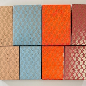 May include: An assortment of rectangular gift boxes in various colors and patterns. The boxes feature designs in peach, light blue, orange, and burgundy. The patterns include paisley and textured floral prints.