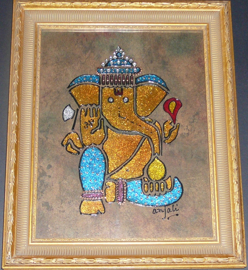 May include: A framed painting of the Hindu deity Ganesha, depicted in a seated pose with a golden body and blue clothing. The painting is decorated with glitter and rhinestones, and the frame is gold.