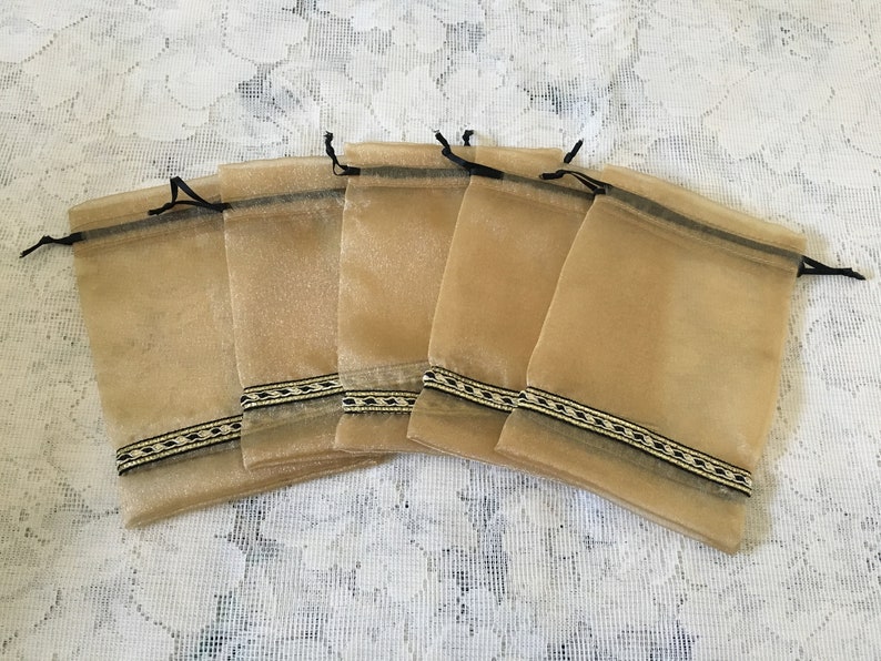 K&ouml;nnte beinhalten: Sechs kleine, beigefarbene Organza-Geschenkbeutel mit schwarzem und goldenem Besatz. Die Beutel haben Kordelz&uuml;ge und sind perfekt f&uuml;r kleine Geschenke oder Mitbringsel.