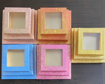 May include: Set of six nested boxes with decorative patterns. The boxes are made of cardboard and have a square shape. The boxes are stacked in three tiers, with two boxes in each tier. The boxes are in various colors, including pink, blue, and gold.