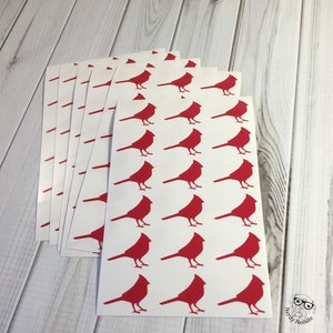 May include: A stack of white sheets with red cardinal silhouettes printed on them. The sheets are arranged in a fan shape.