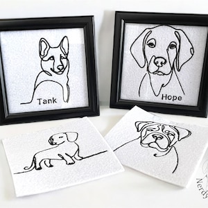 May include: Black framed artwork featuring line drawings of dogs. Two framed pieces display dog portraits with names "Tank" and "Hope". Two additional unframed pieces show dog illustrations. The artwork is on a white background.