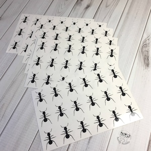 May include: A sheet of white paper with a repeating pattern of black ant silhouettes. The paper is folded into multiple sheets.