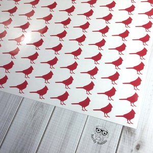May include: A sheet of red cardinal bird stickers on a white background. The stickers are arranged in a repeating pattern.