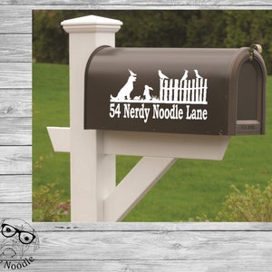 May include: A white vinyl mailbox decal with a dog, rabbit, and birds in front of a picket fence. The text "54 Nerdy Noodle Lane" is below the image.