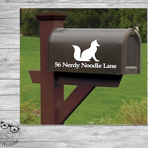 May include: A brown mailbox with a white fox silhouette and the text "56 Nerdy Noodle Lane" on the front.