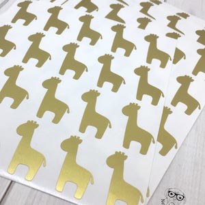 May include: A sheet of gold foil stickers featuring a repeating pattern of giraffe silhouettes. The stickers are on a white background.