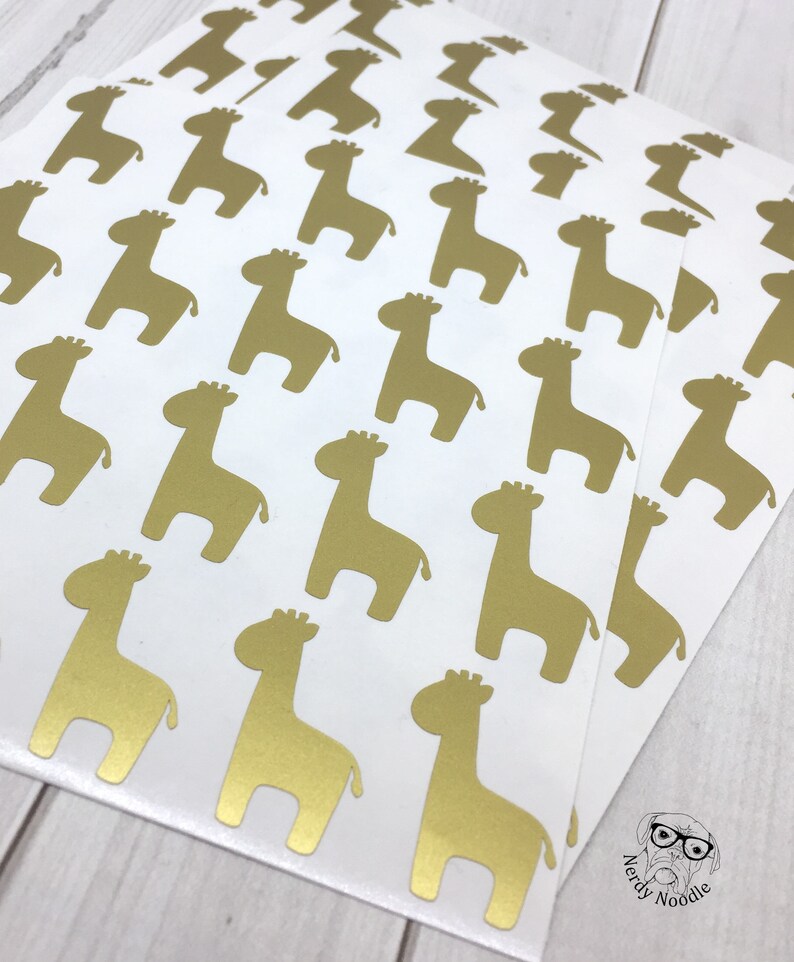 May include: A sheet of gold foil stickers featuring a repeating pattern of giraffe silhouettes. The stickers are on a white background.