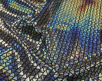 Może przedstawiać: Zbliżenie na tęczową tkaninę z geometrycznym wzorem czarnych trójkątów. Tkanina ma holograficzne wykończenie, które mieni się różnymi kolorami.