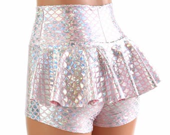 Puede incluir: Shorts de color rosa y plateado iridiscente con una falda de volantes superpuesta. Los shorts tienen un patrón de escamas de sirena.