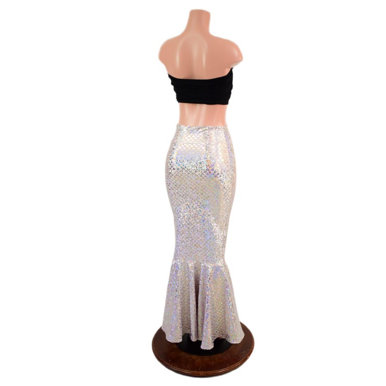 May include: A two-piece outfit consisting of a black strapless bandeau top and a floor-length, high-waisted mermaid skirt. The skirt features a shimmering, iridescent scale-like pattern that reflects light with a metallic, holographic finish.