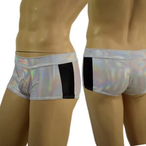 May include: Silver holographic shorts with a black vertical panel on the side. The shorts have a low-rise waist and a form-fitting design. The fabric has a shimmering, iridescent quality.