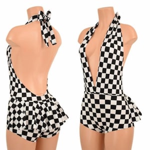 May include: A black and white checkered halter romper featuring a deep V-neckline, a tie-back neck closure, and a flared skirt overlay attached to the shorts. The garment displays a consistent geometric checkerboard pattern throughout the entire piece.