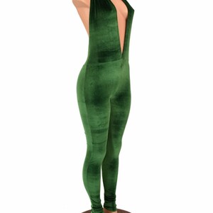 May include: A green velvet jumpsuit with a plunging neckline and halter tie. The one-piece garment is form-fitting, with long sleeves and legs. The jumpsuit is displayed on a mannequin.