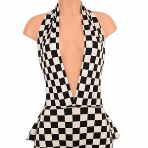 May include: A black and white checkered bodysuit featuring a deep plunging halter neckline and a flared peplum waist detail. The garment is displayed on a mannequin and showcases a consistent geometric square pattern throughout the entire piece.